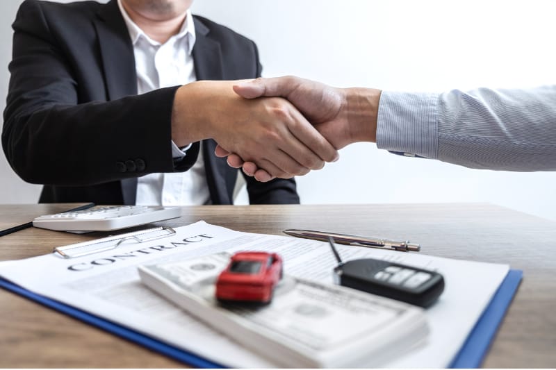 Customer signing car leasing agreement with dealership representative